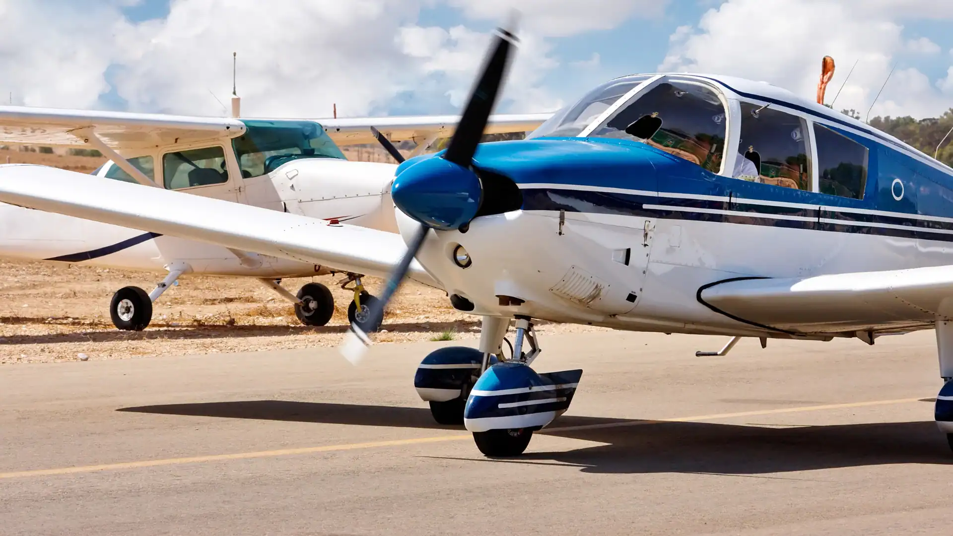 Small private airplane parked on runway with clear sky in background.
