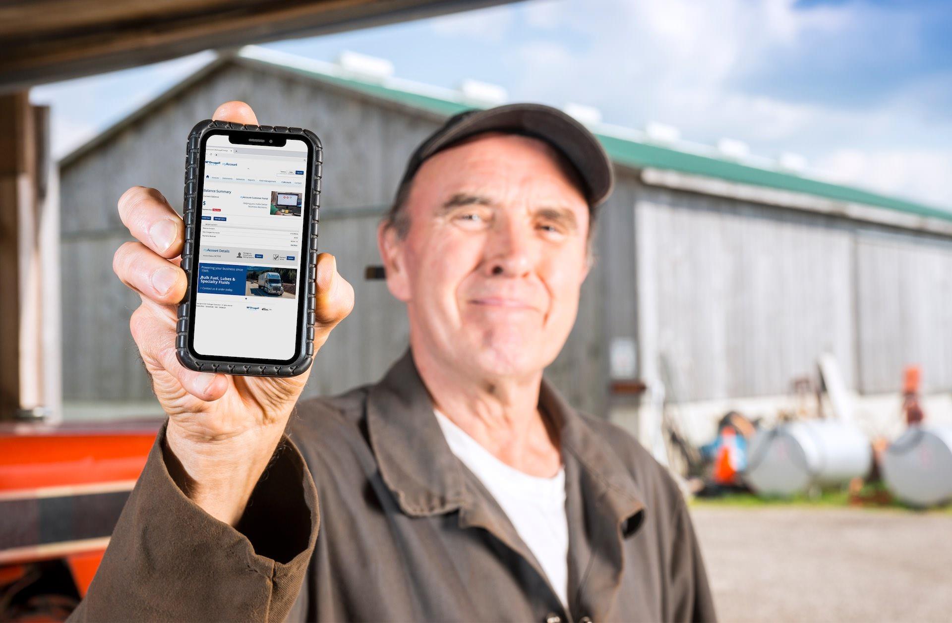 A man at a farm holding his mobile phone showing Mcdougall myAccount website