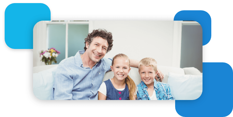 father sitting with kids on a couch smiling at camera
